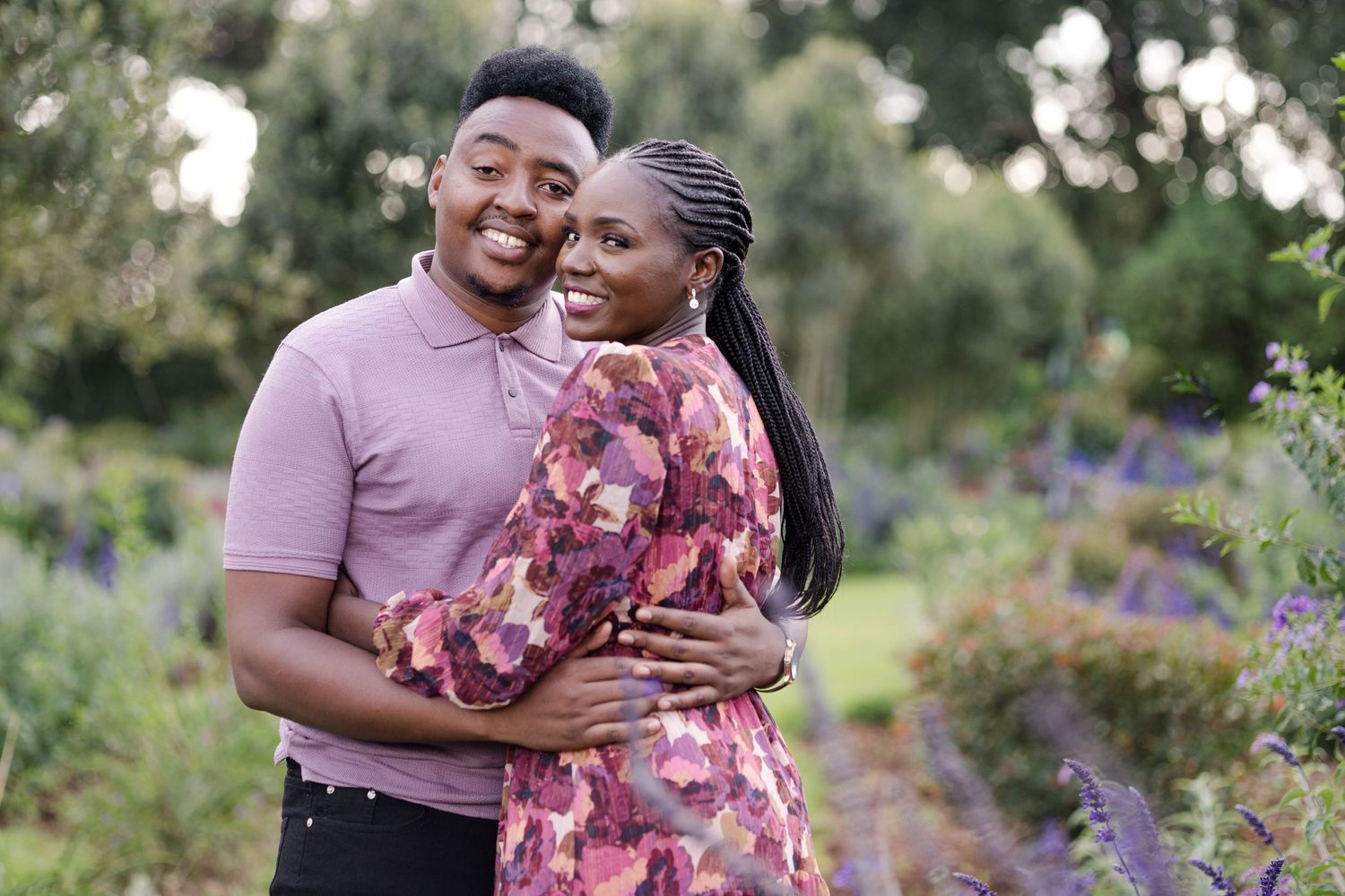 Couple's portrait in Naishola's lavender garden. They're both in purple. They're hugging, both smiling at camera. Ikigu George Photography.