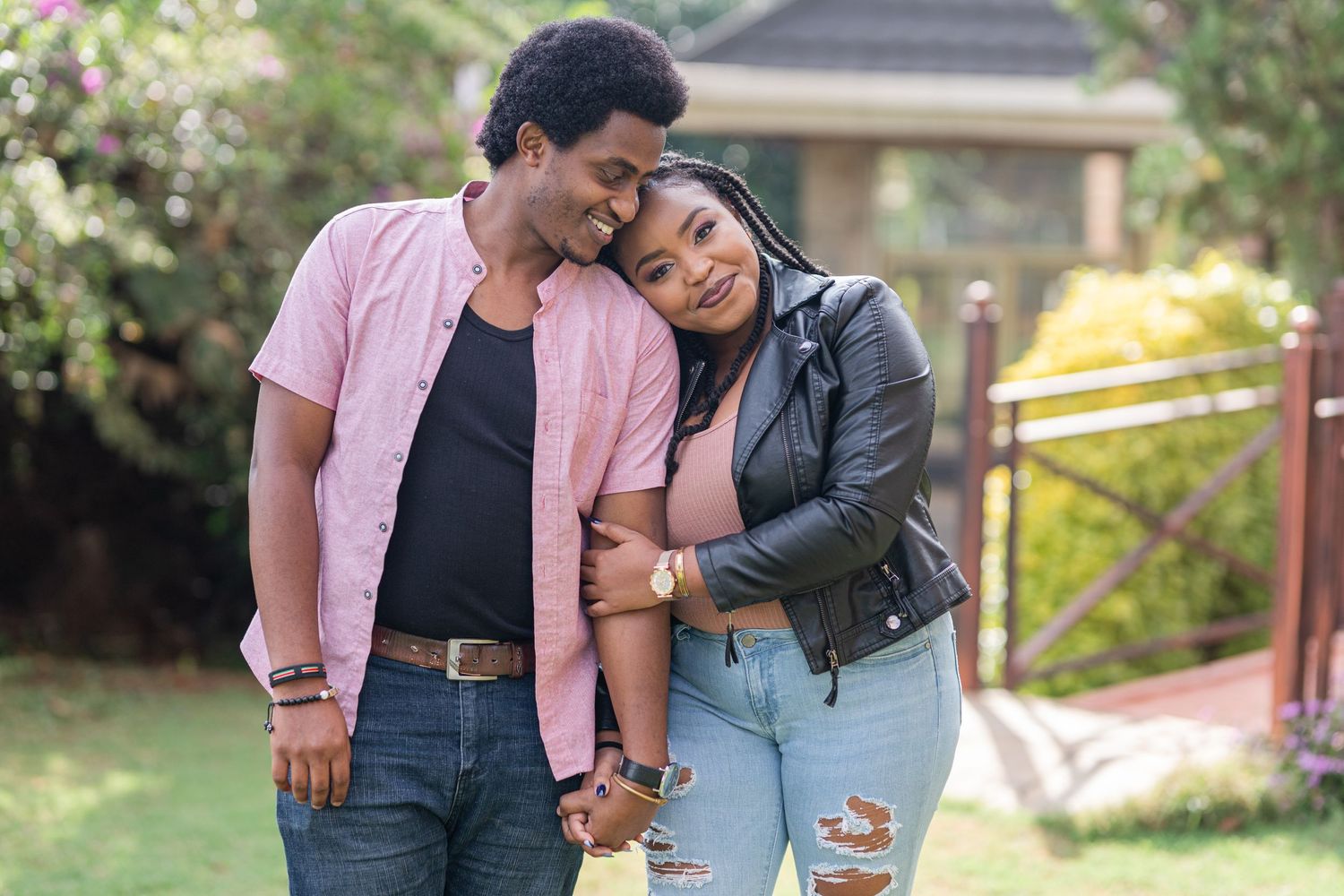 Portrait of a couple standing next to one another, in garden. Woman's head leaning on man's shoulder. Ikigu George Photography.