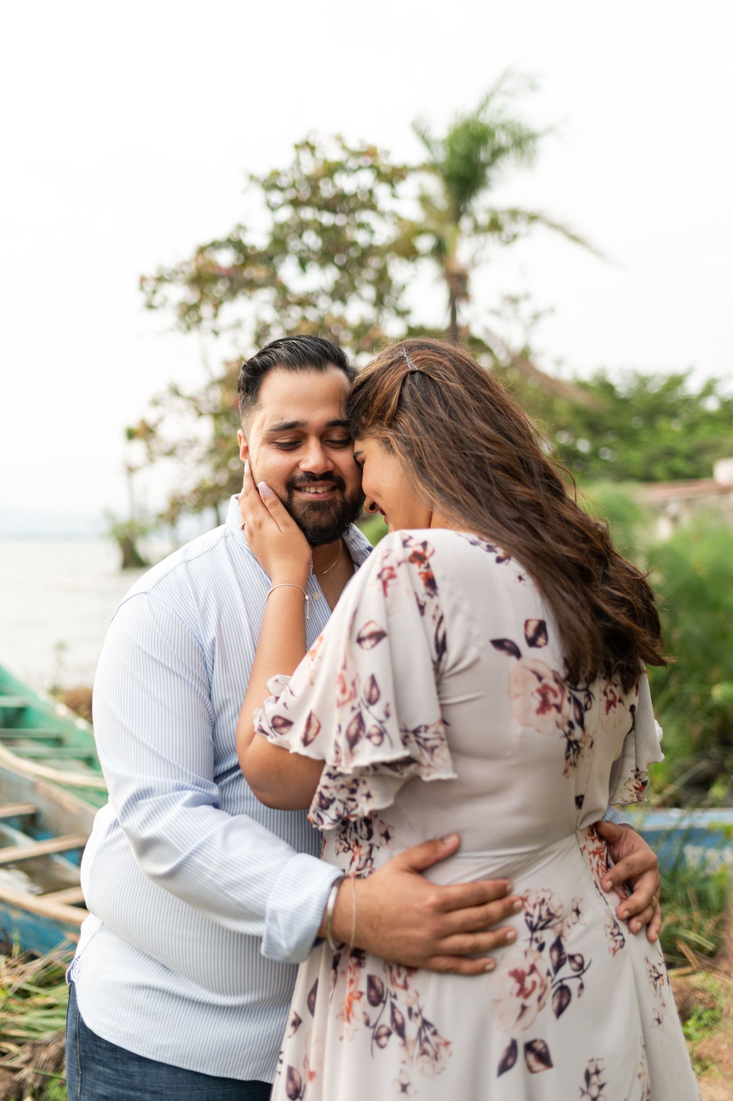 Indian couple's engagement portraits by Lake Victoria. They're embracing, with big smiles on their faces. Ikigu George Photography.