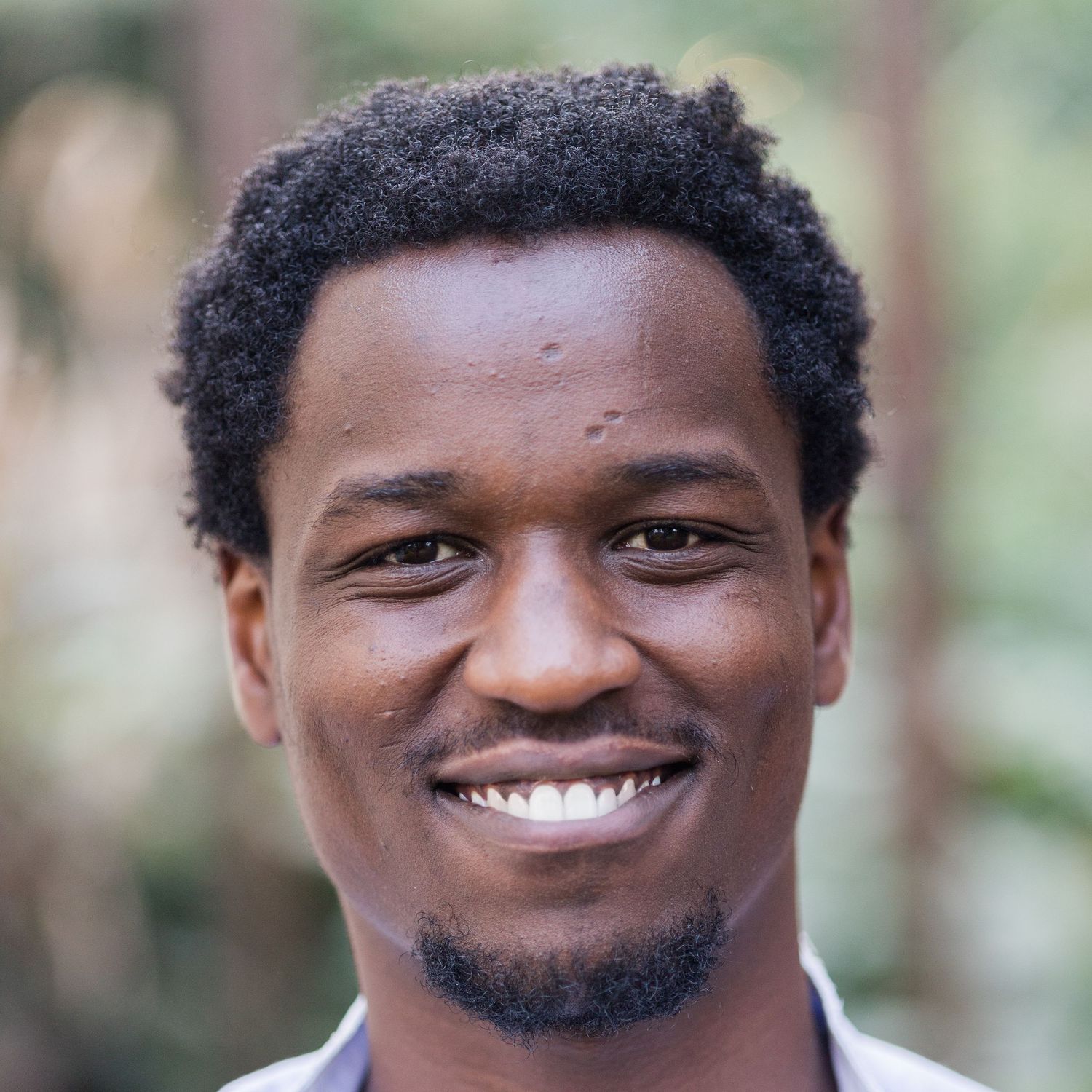 Headshot of Ikigu George. Big fro and big smile.