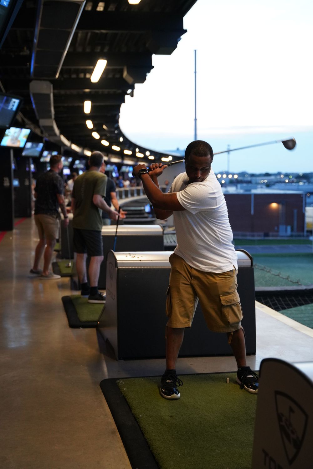 Golfer takes a swing at an indoor driving range facility.