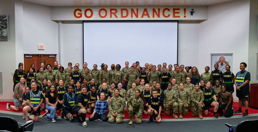 Large group of military personnel pose together under a Go Ordnance sign.
