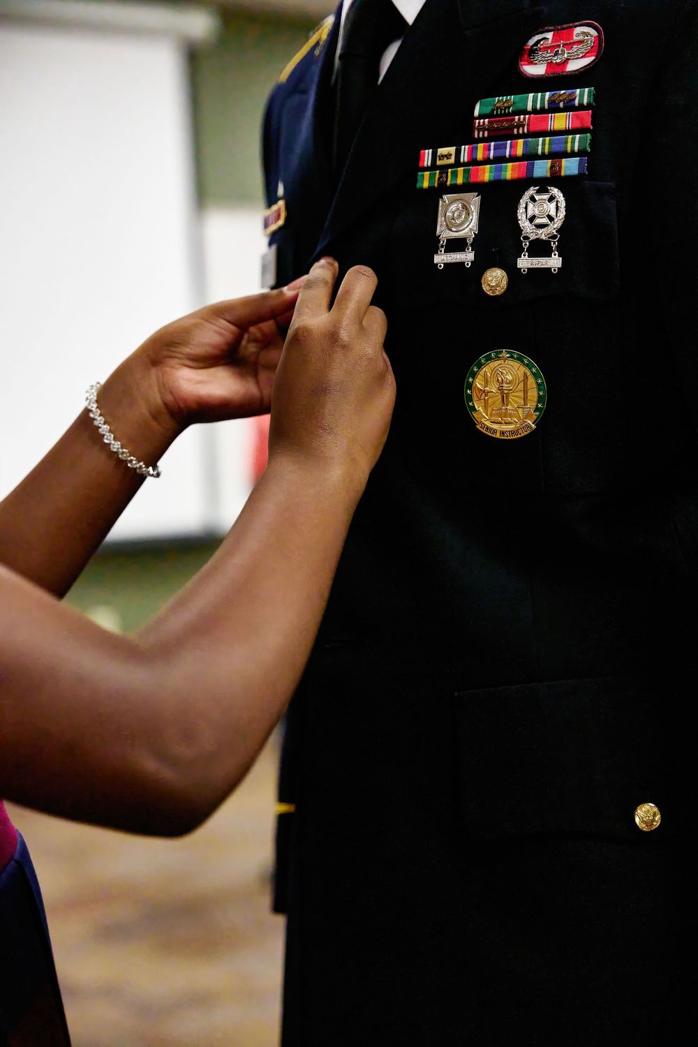 A woman pins a medal onto a decorated U.S. Army dress uniform during a military ceremony.
