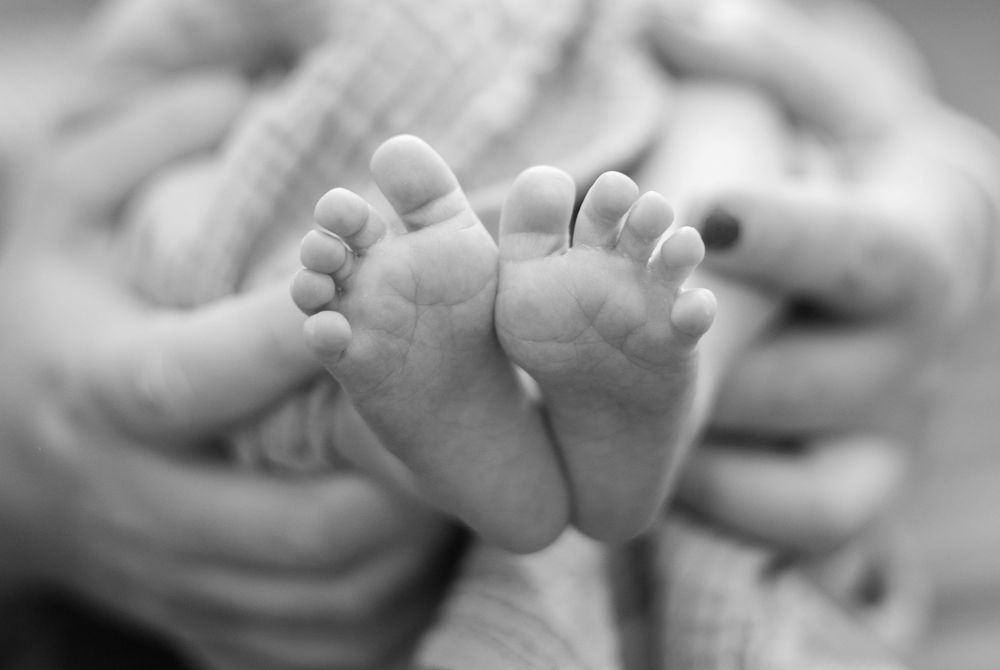 Close-up black and white photo of tiny newborn baby feet.