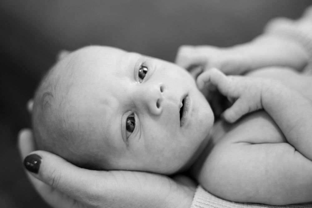 Baby resting on soft surface while being cradled.