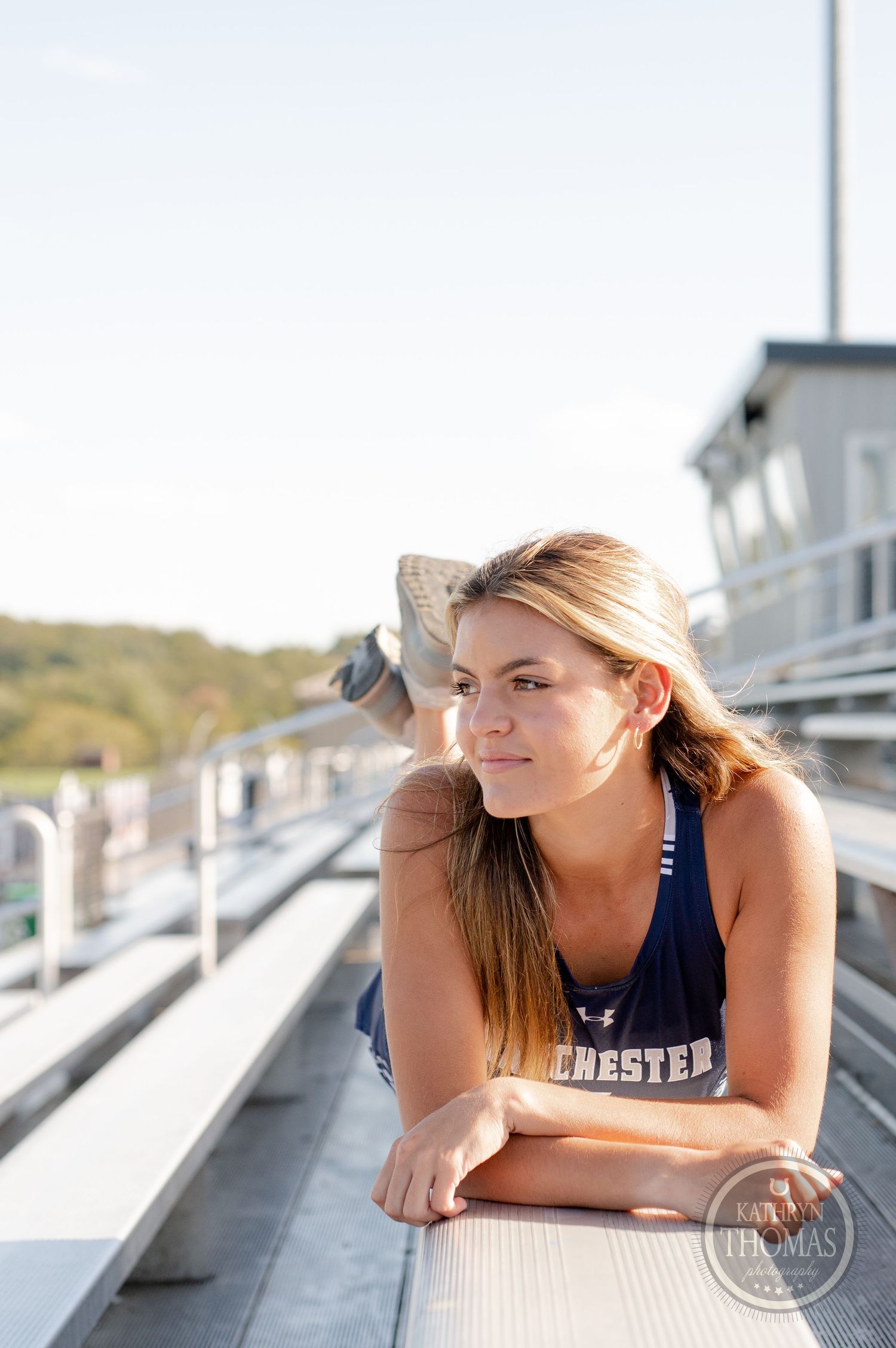Athletic person in navy uniform reclines on stadium bleachers during golden hour.