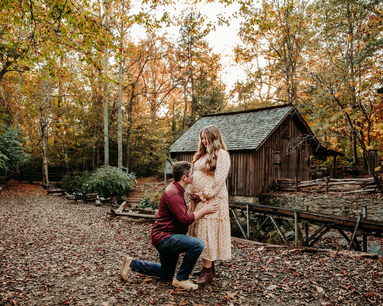 Autumn photoshoot near rustic wooden buildings with fallen leaves.