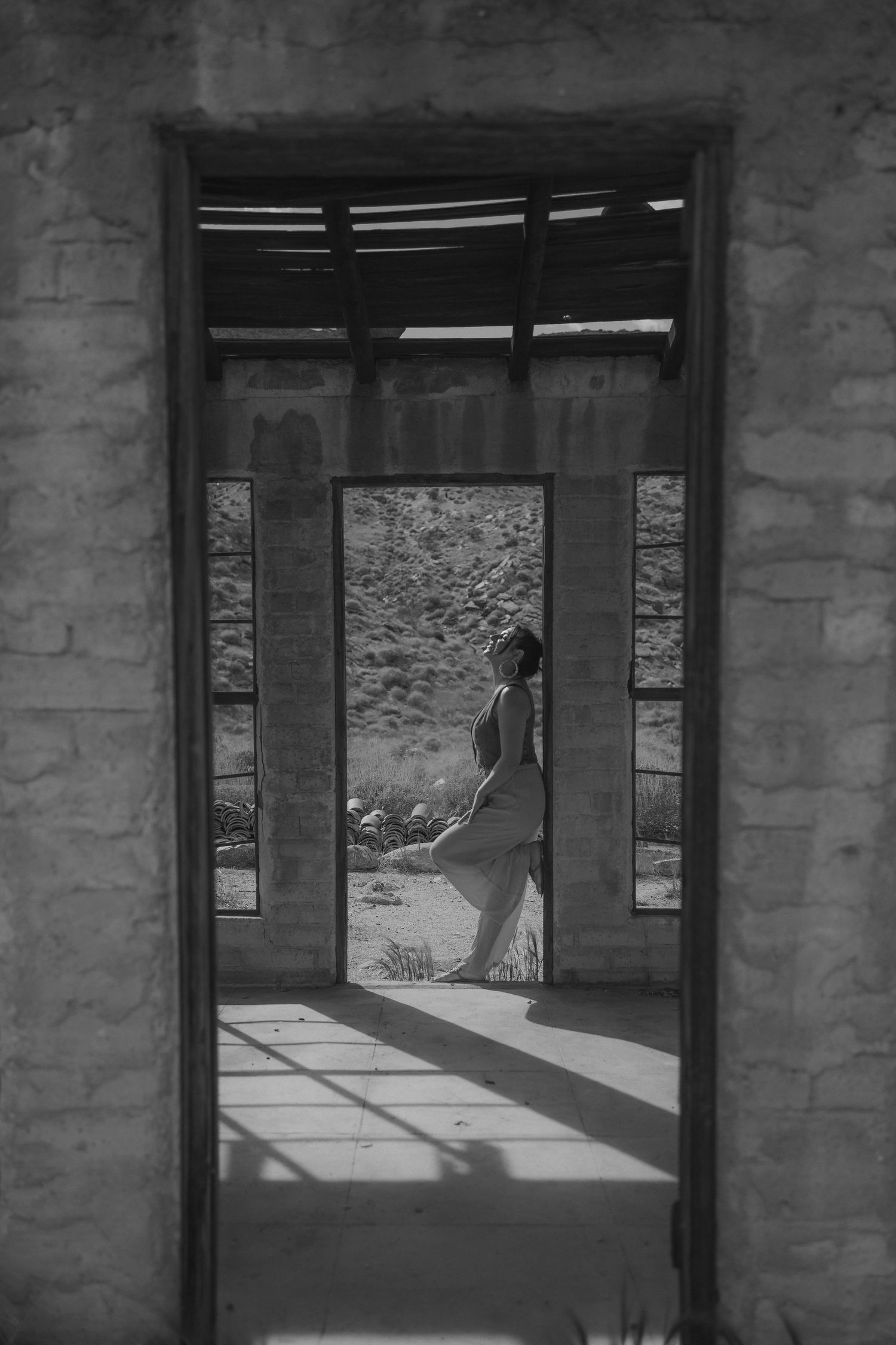 Silhouette of person seen through doorway of brick building in black and white photograph.