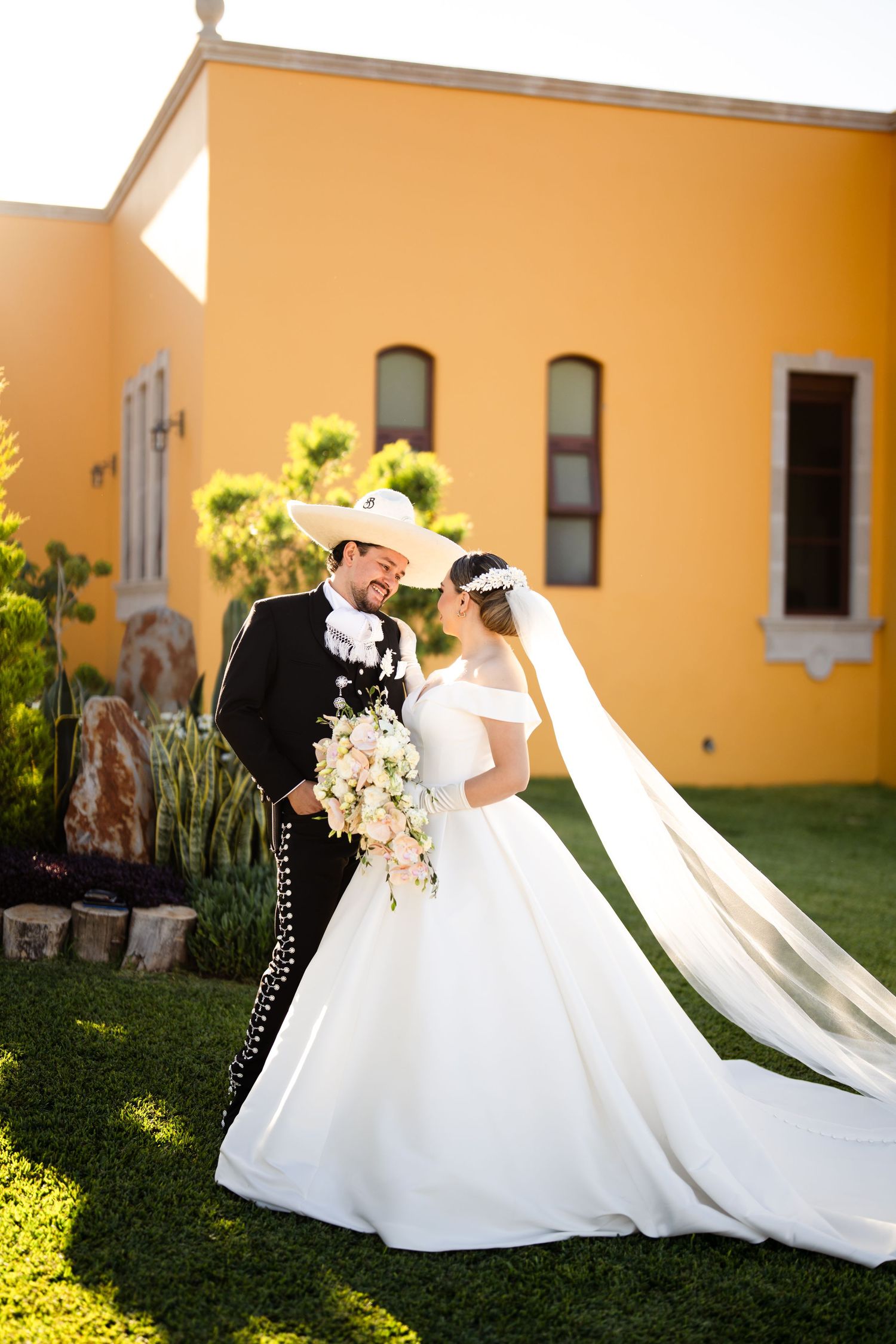 Series of romantic bridal portraits with flowing white gowns against yellow building in sunlight.