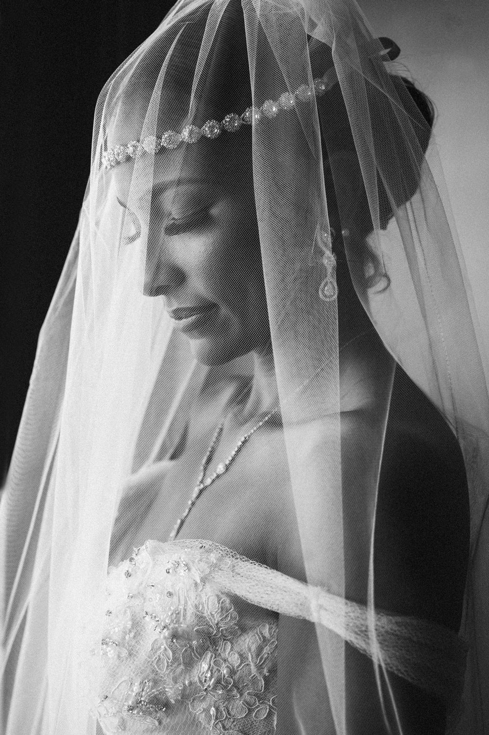 Artistic black and white bridal portrait with delicate lace-trimmed veil.