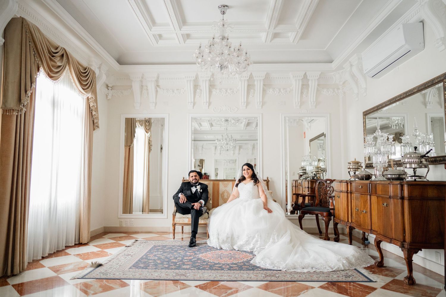 Elegant white ballroom with ornate ceiling details and classic wedding decor.