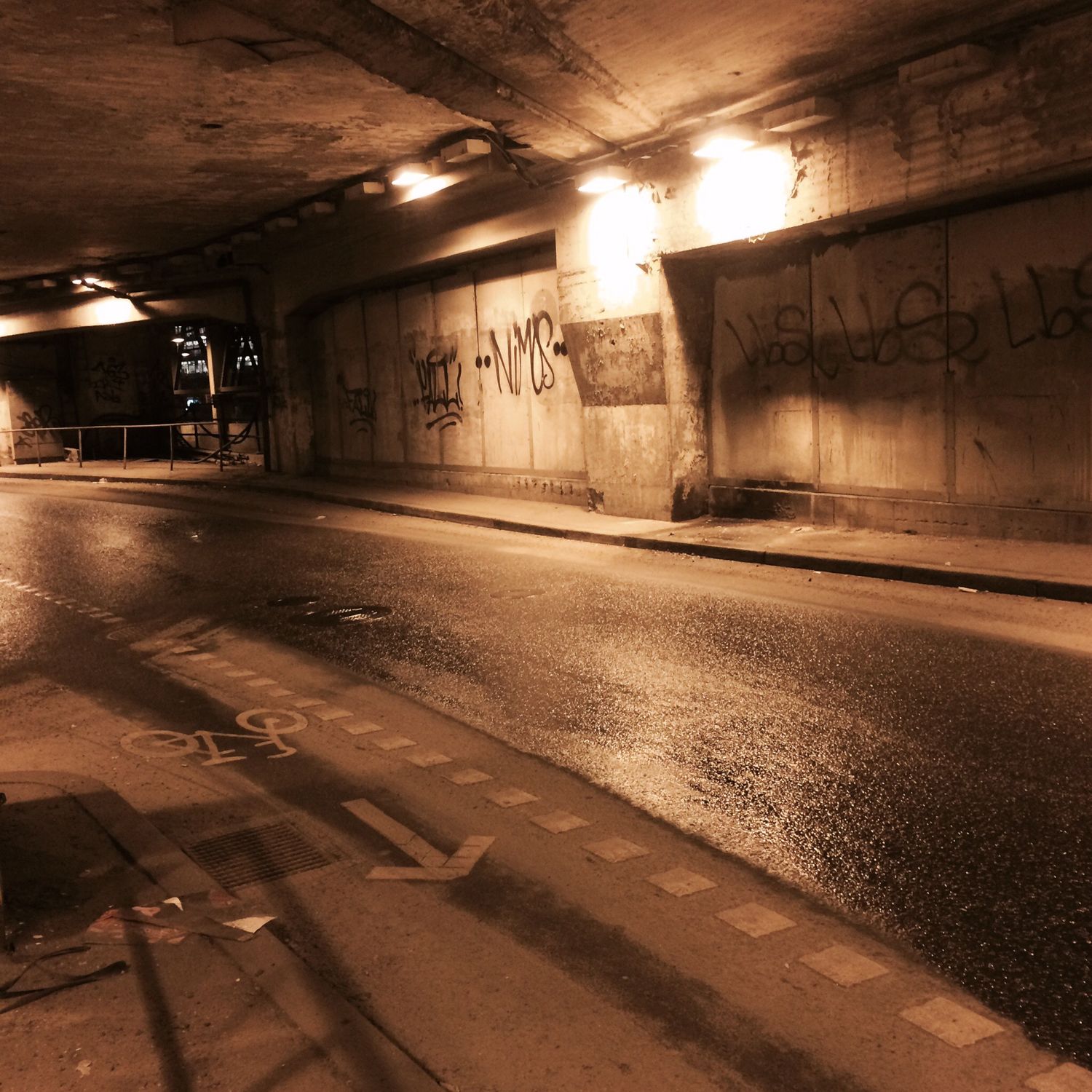 Car road, under a tunnel. some graffiti tags on walls.