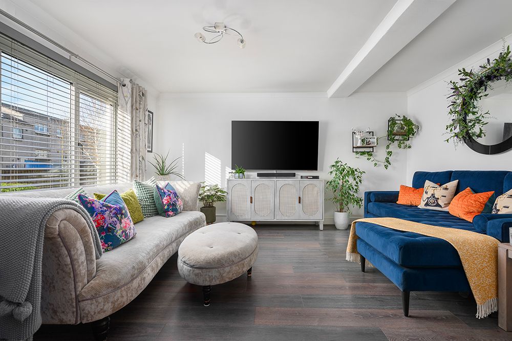 Modern bright and airy living area with dual sofas and colourful accessories. West lothian estate agents.