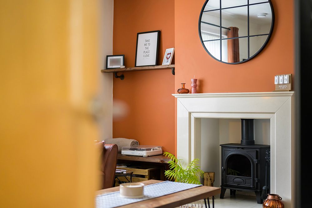 modern living room with log burning fire and orange accent colour. Air bnb listing for stirling client