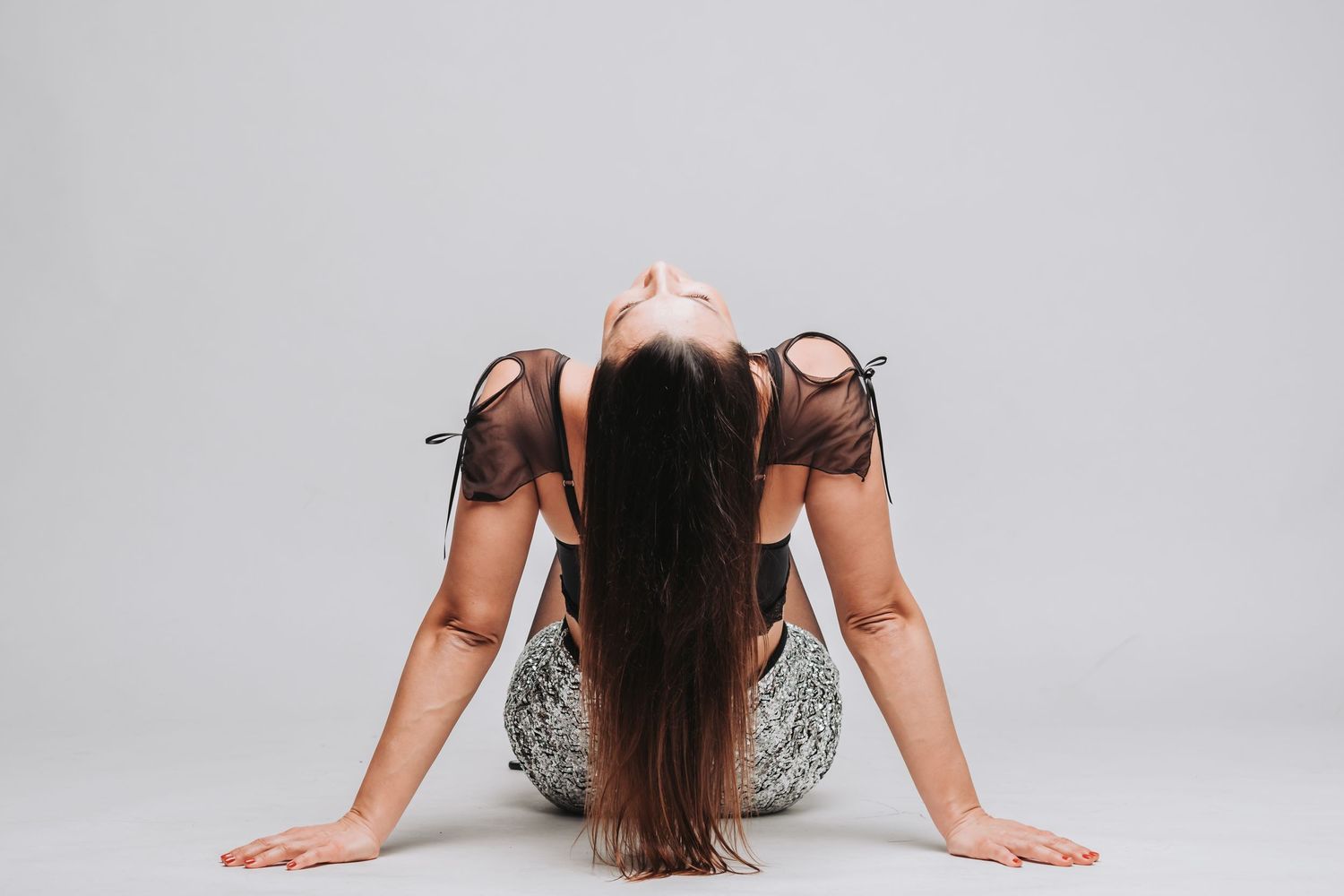 Person with long dark hair poses on floor in artistic dance-inspired position.