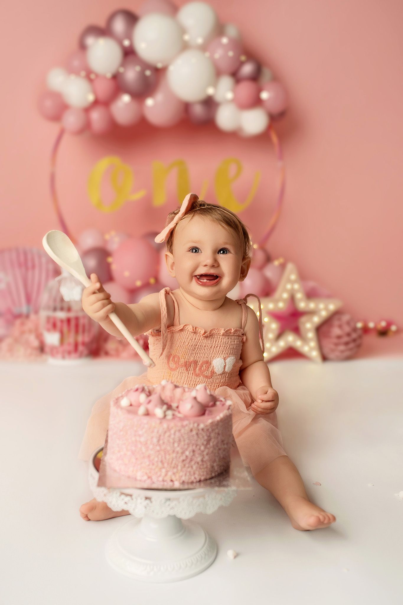 Baby girl eating cake during birthday session in studio