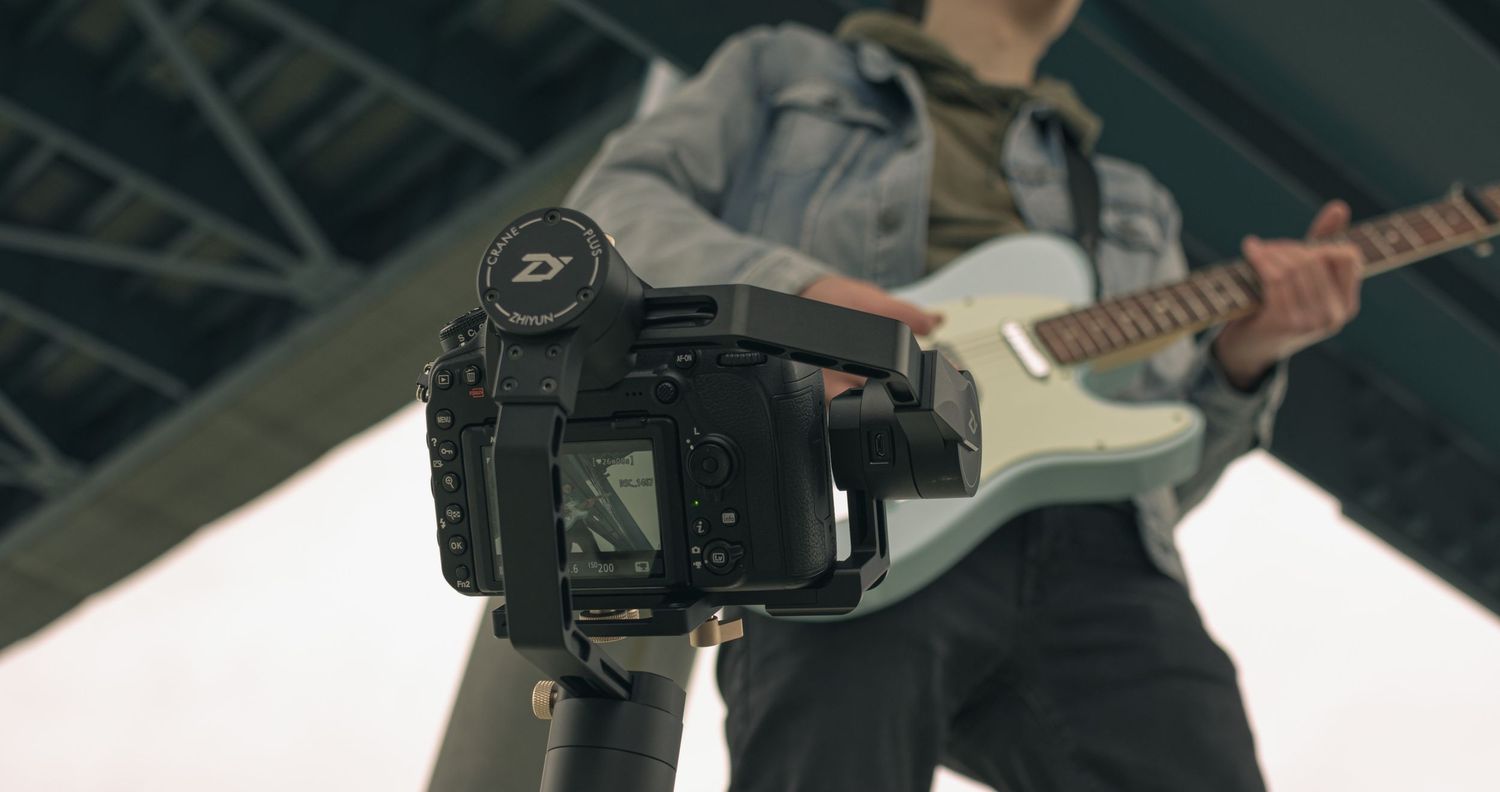 Digital camera filming a guitarist performing on stage in low light conditions.