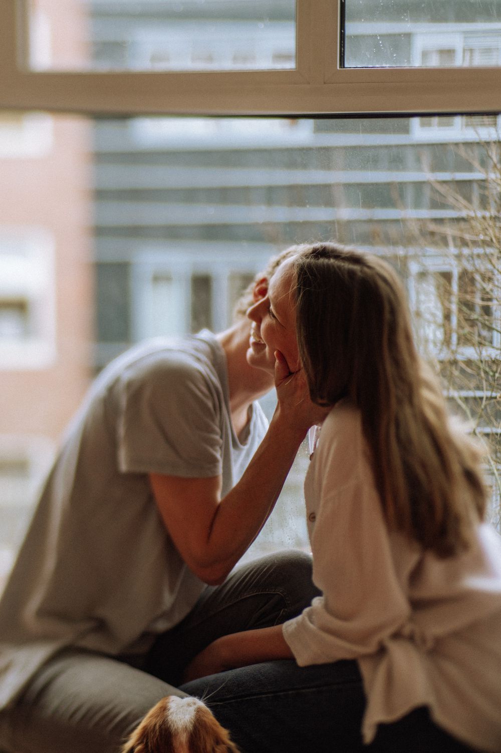 Intimate moment between two people near a bright window.