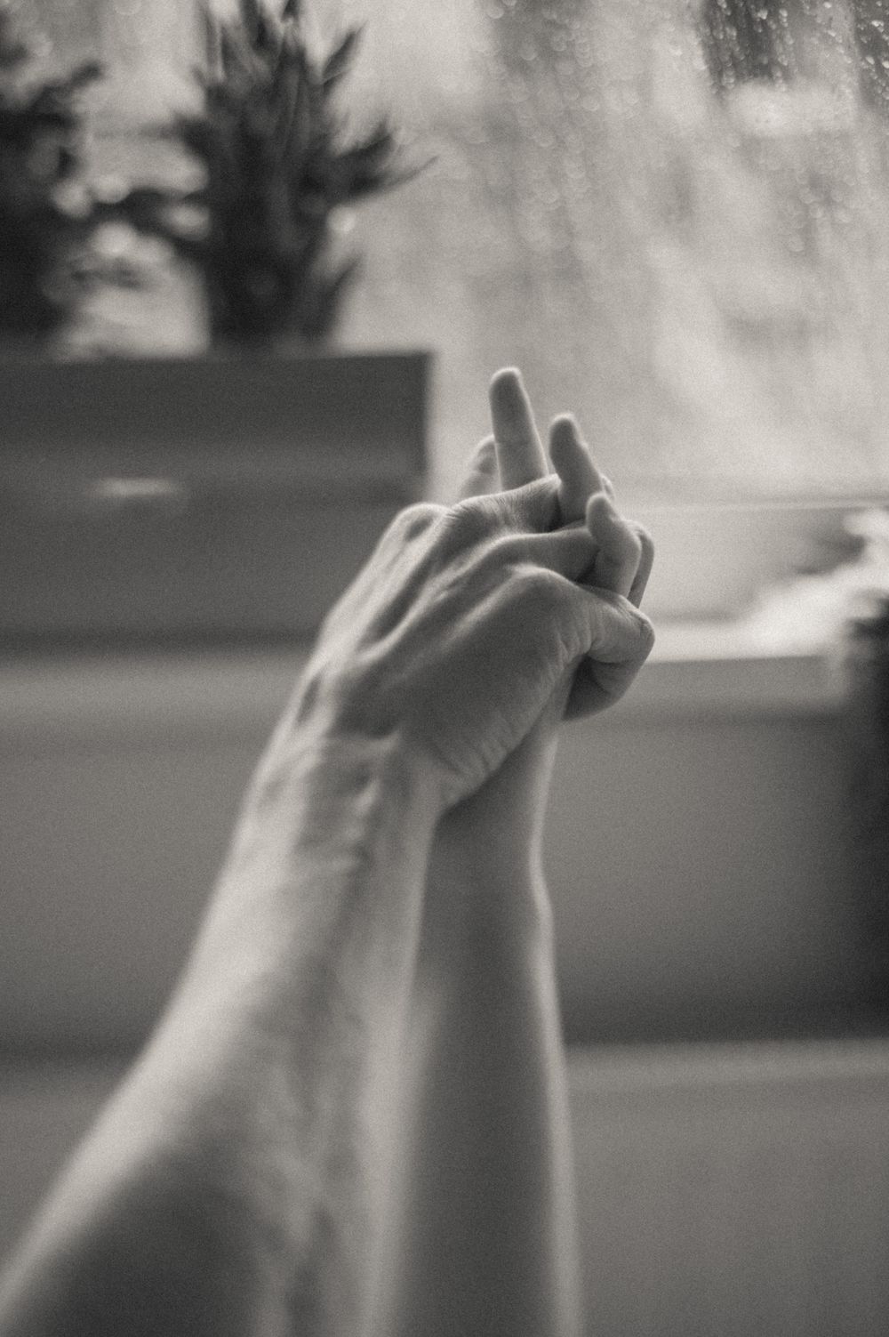 Artistic black and white close-up of intertwined hands.