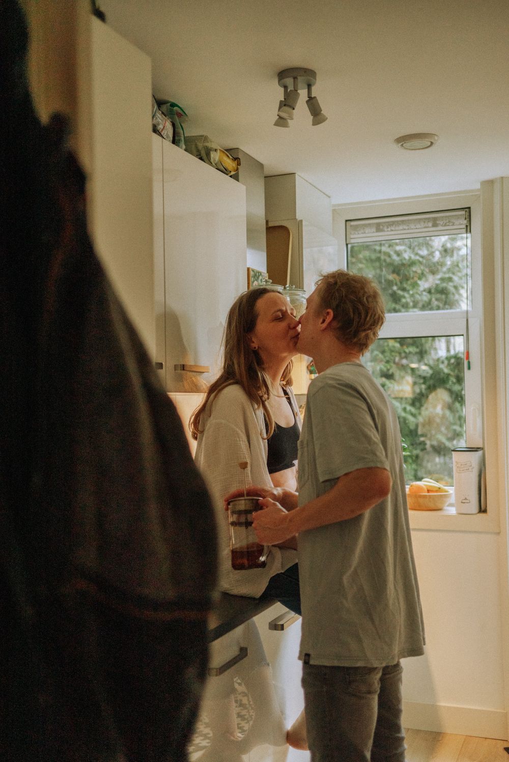 Couple sharing an intimate moment in bright kitchen setting.