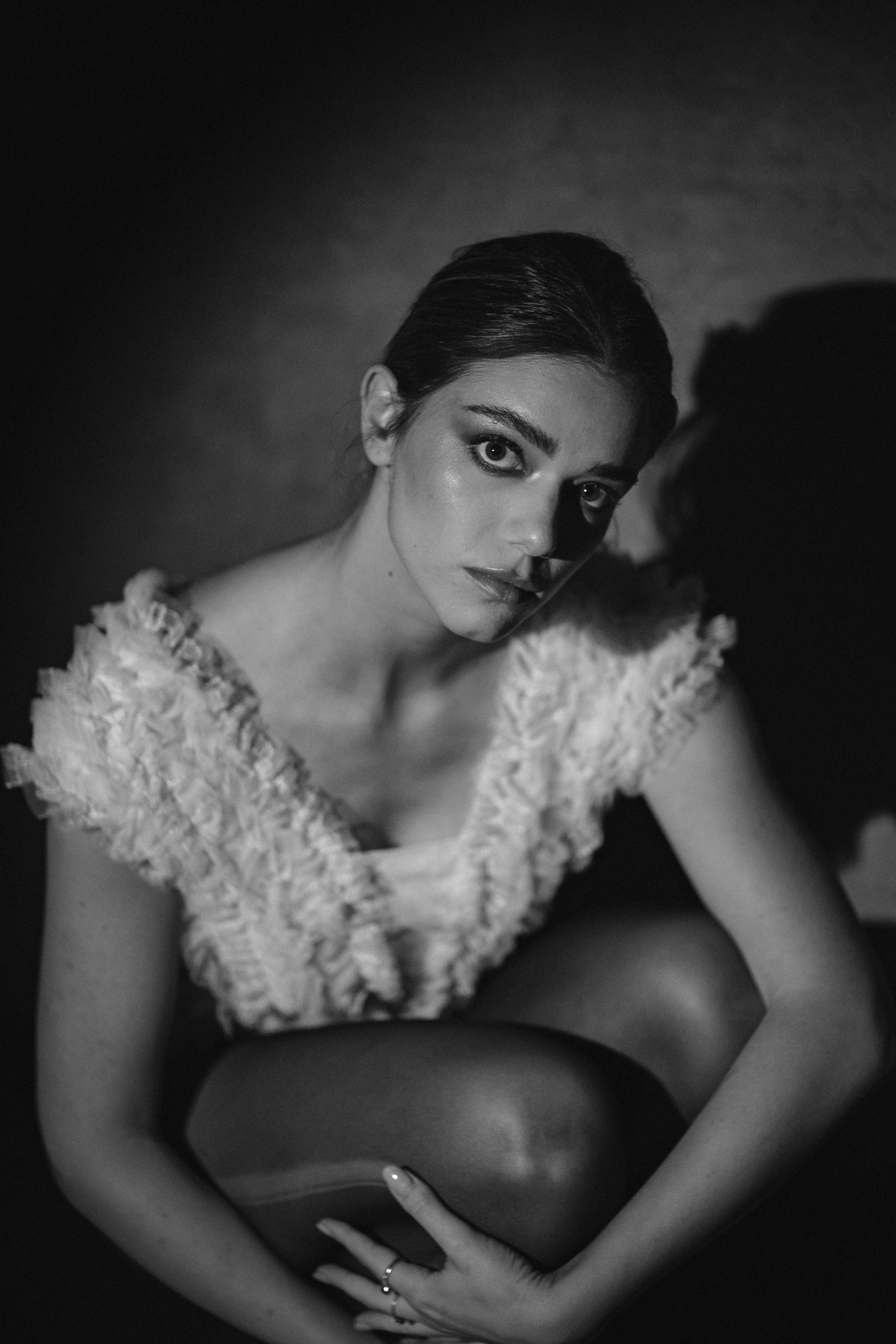Dramatic black and white fashion photo featuring white ruffled top and artistic shadow play.