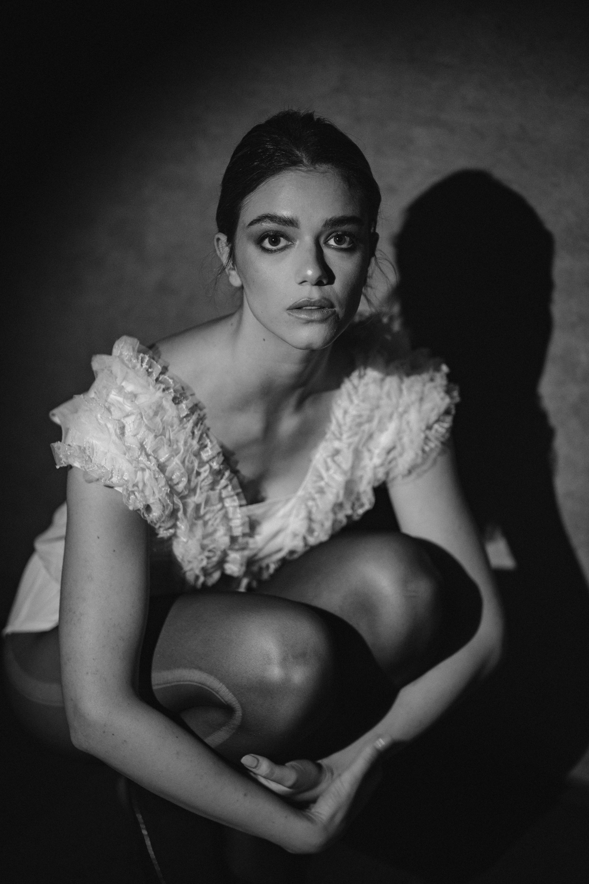 Artistic monochrome portrait showing model in white textured dress with strong side lighting.