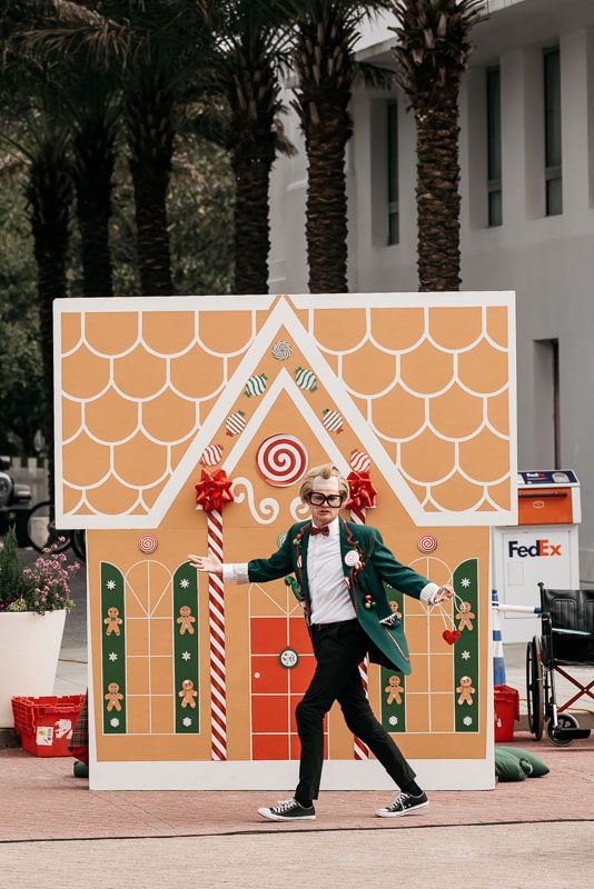 Holiday display with gingerbread house decorations and people walking in front of post office.