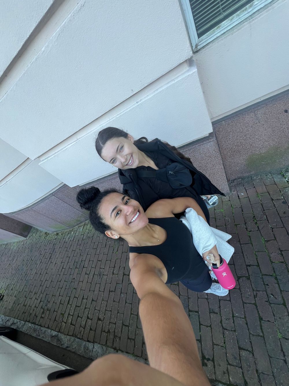 A couple taking a selfie together outdoors on brick pavement.