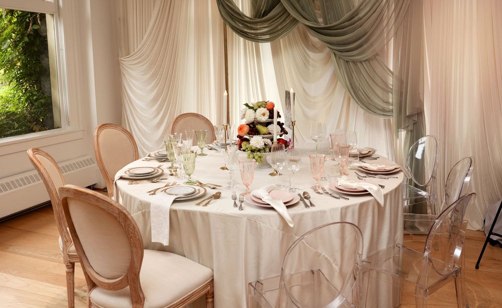 Elegant white table setting with floral centerpiece and french provincial chairs.
