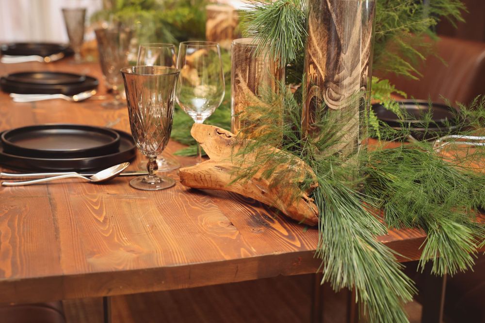 Elegant table setting with pine branches and glassware on a wooden table.