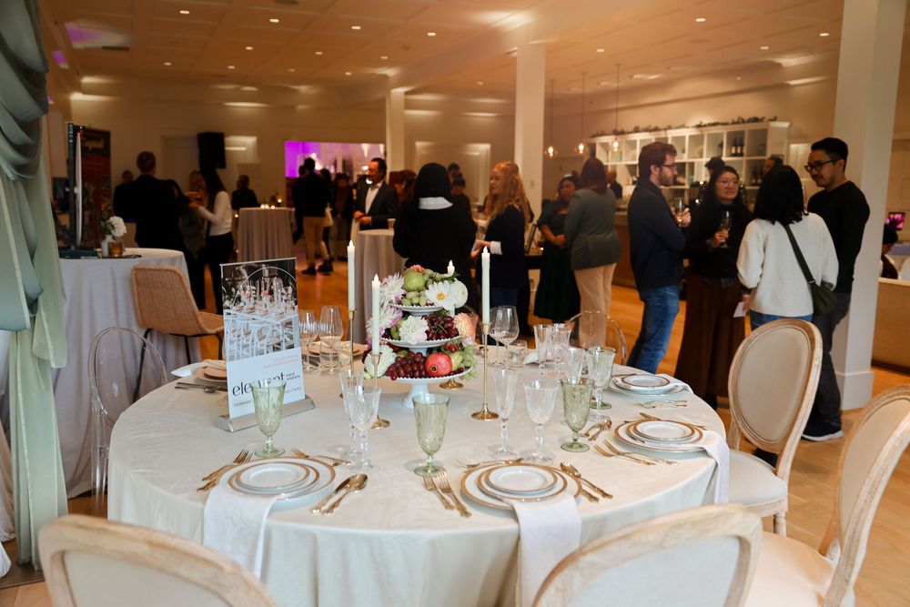 Formal dining setup with round tables, white linens and place settings at an elegant event venue.