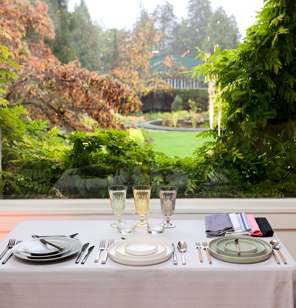 Formal place setting with champagne flutes overlooking garden landscape.