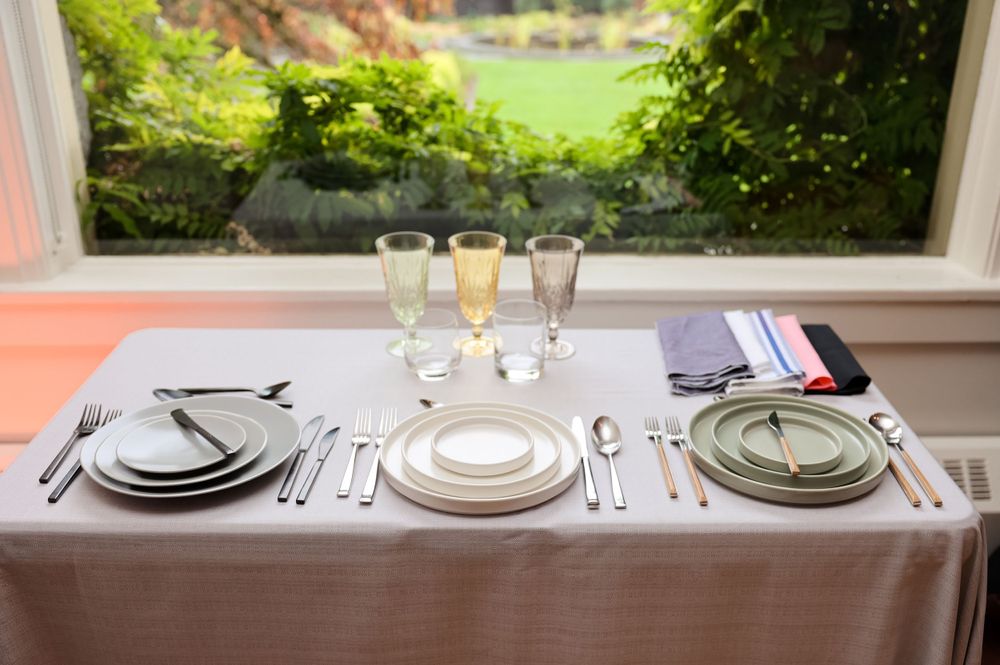 Elegant table setting for three with champagne flutes and formal dinnerware.