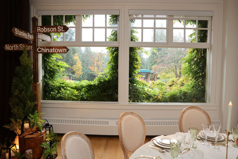 Dining room with large windows overlooking lush garden scenery.