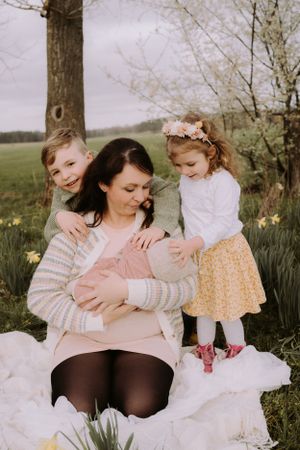 A spring family portrait with daffodils blooming under a tree in soft natural light.