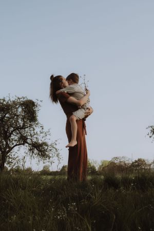 A silhouette of a tender embrace between two figures against a dusky sky in a natural field setting.