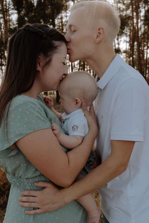 An intimate family portrait captured in warm sunset lighting among pine trees.