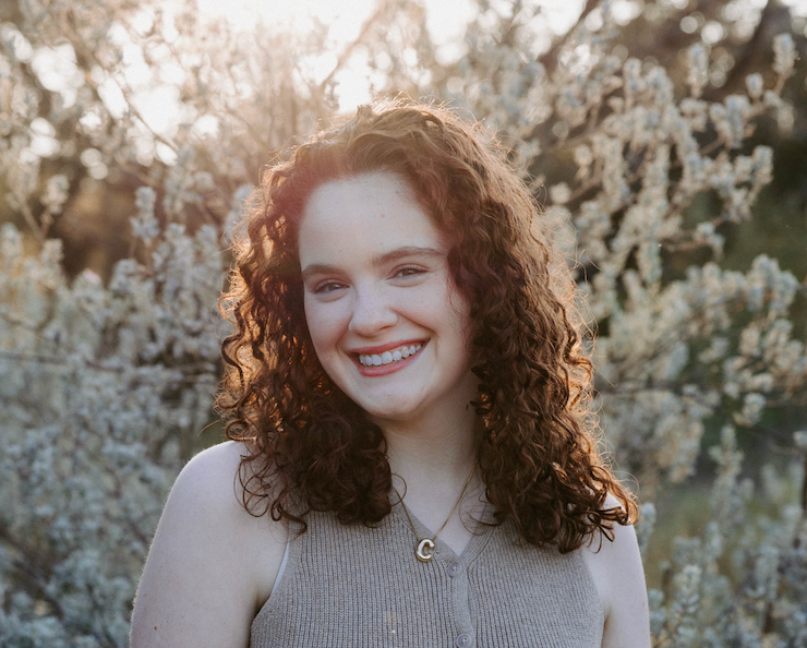 San Antonio Photographer Headshot. Person in beige top smiles warmly against backdrop of blooming spring flowers.