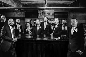 Black and white photo of groom and groomsmen posing at a bar under a Prohibition sign.