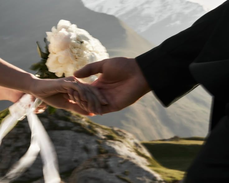 Delicate white rose petals being held against a blurred outdoor background.