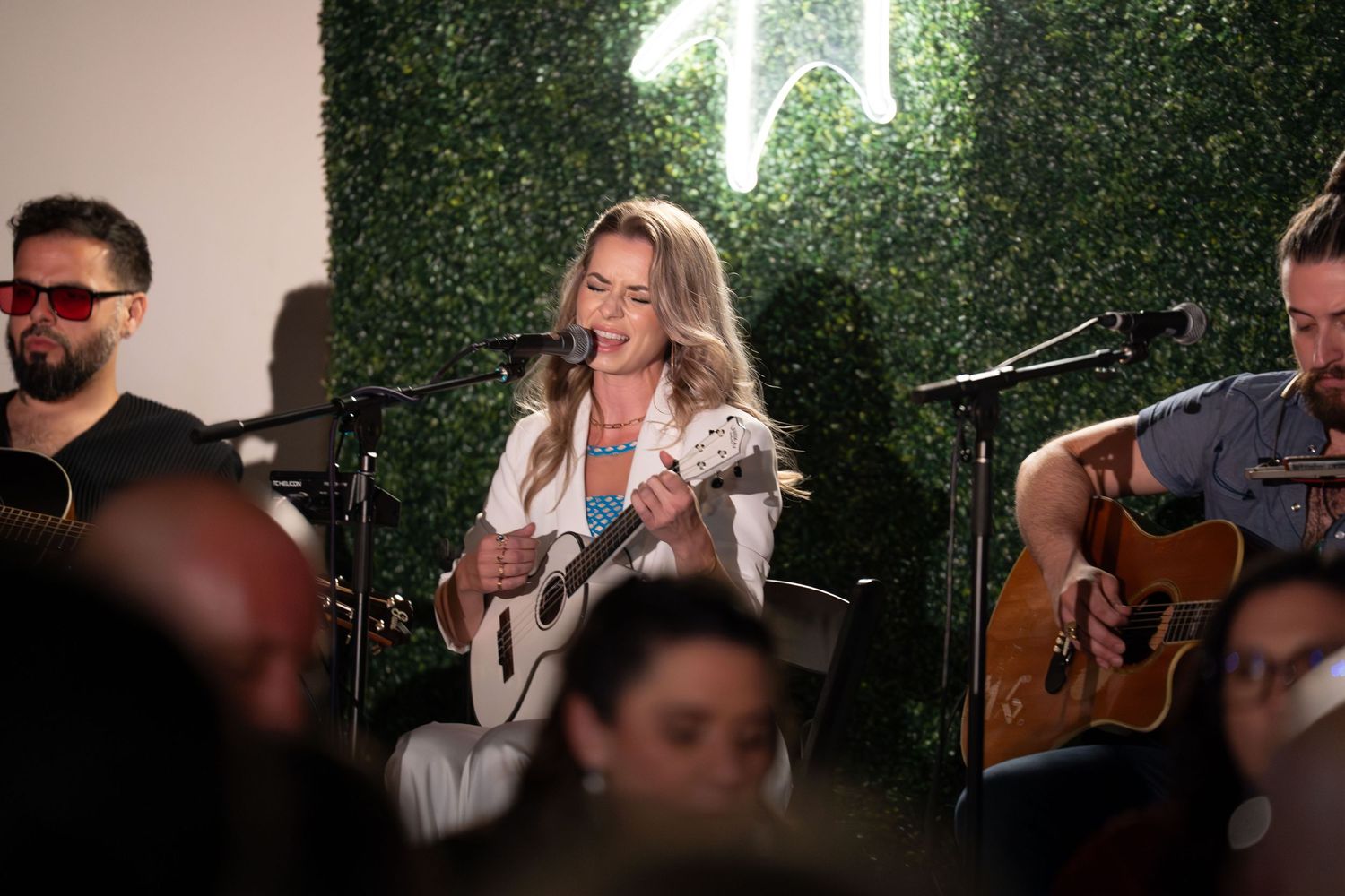 Musicians performing together during an intimate acoustic session with guitars and microphones.