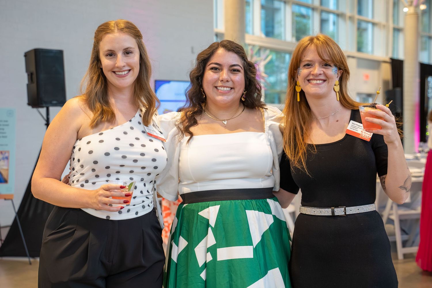 A group of people pose together at a professional networking or social event in a bright indoor space.