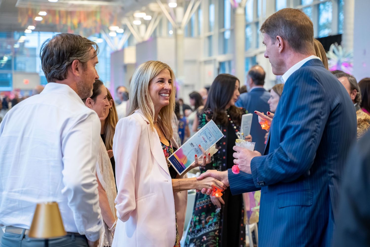 Business professionals networking and socializing at a crowded corporate event with drinks and conversation.