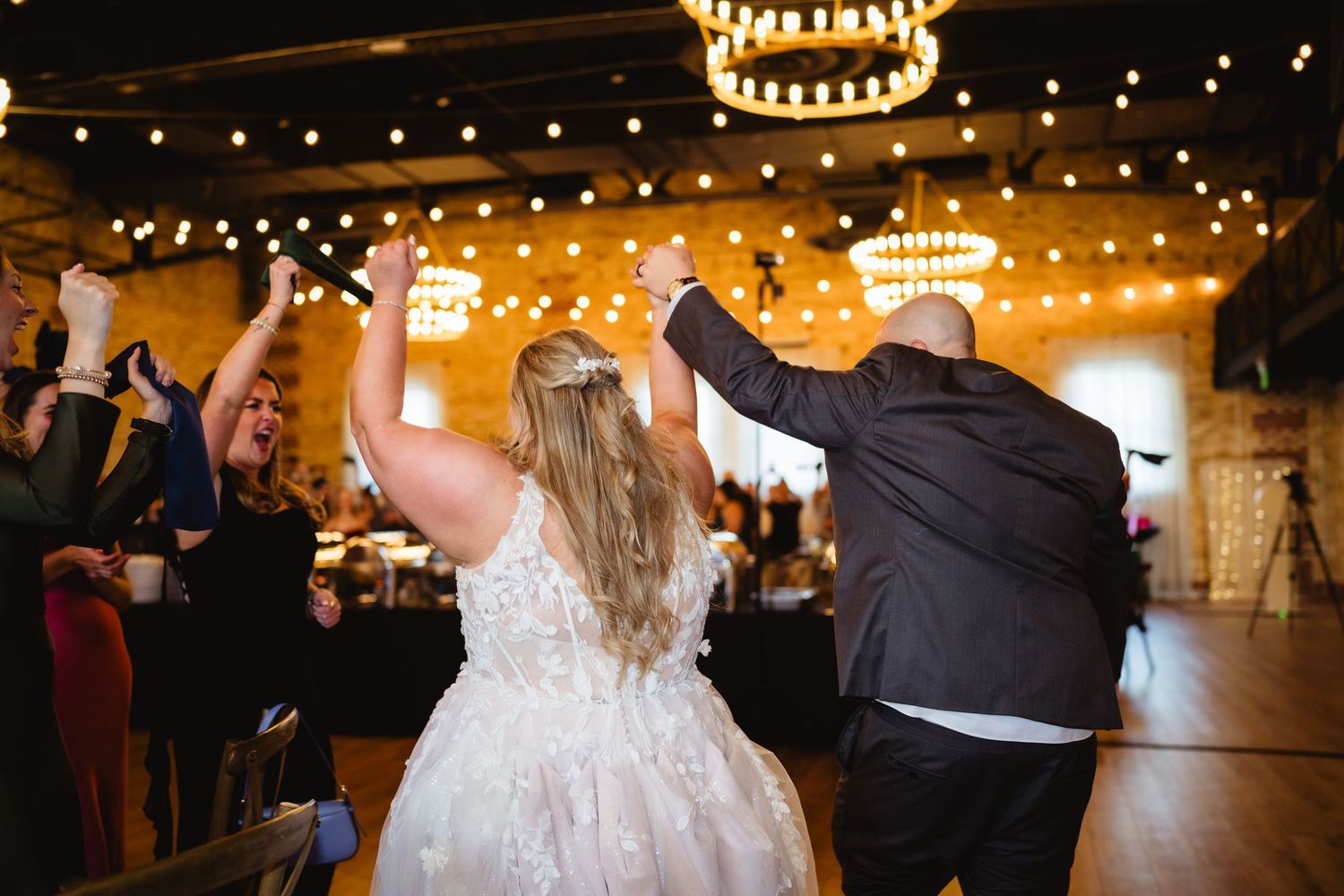 Wedding reception venue decorated with elegant chandeliers and string lights creating a warm ambiance.
