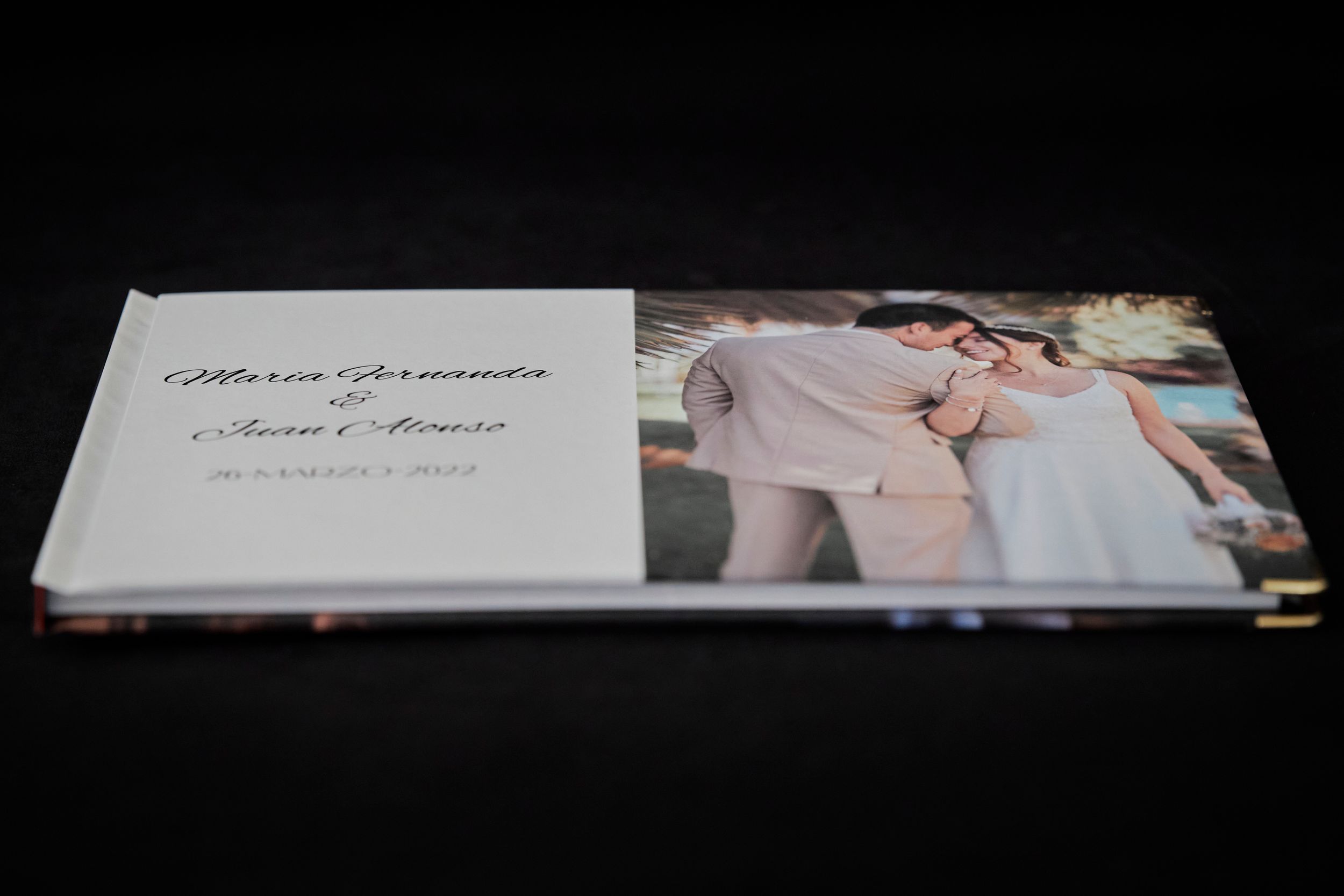 Wedding photo album displayed on dark background showing elegant white hardcover design.