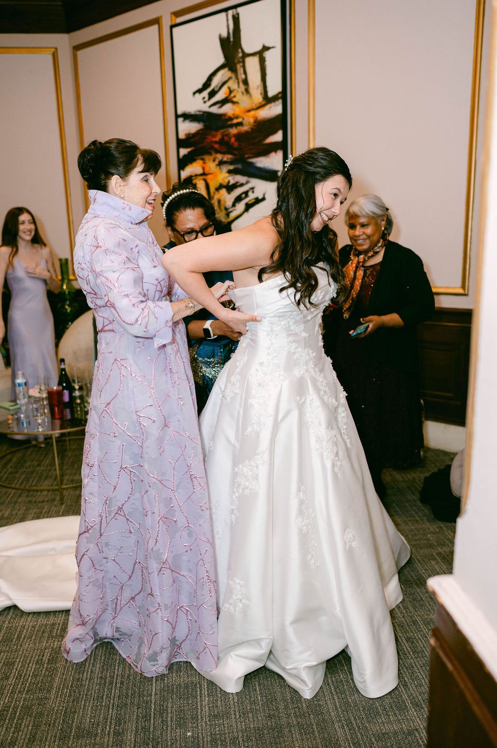 People in formal attire dance and socialize at an indoor wedding reception.