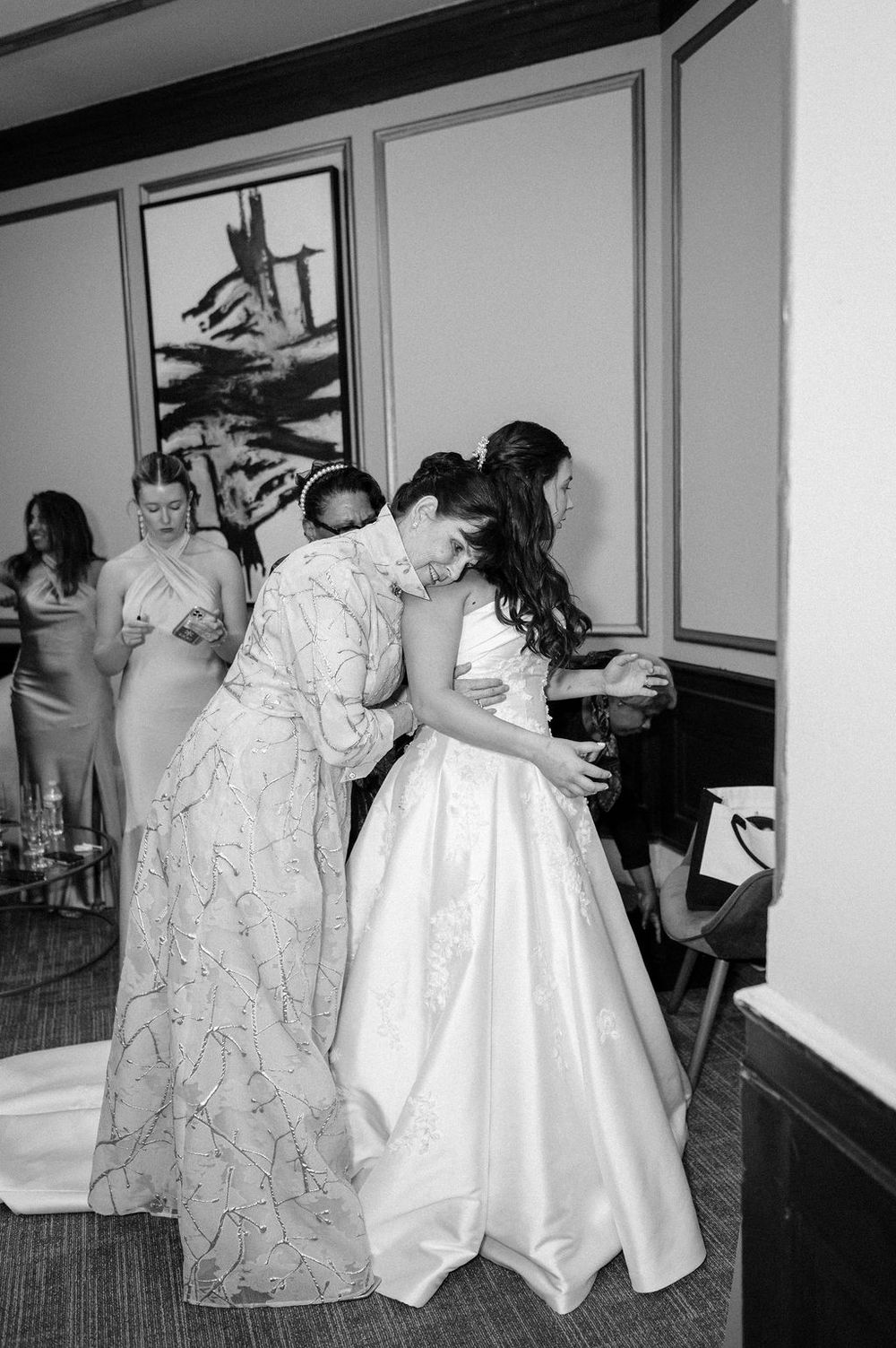 A sequence of black and white photos showing people in formal dresses walking through an elegant indoor space.