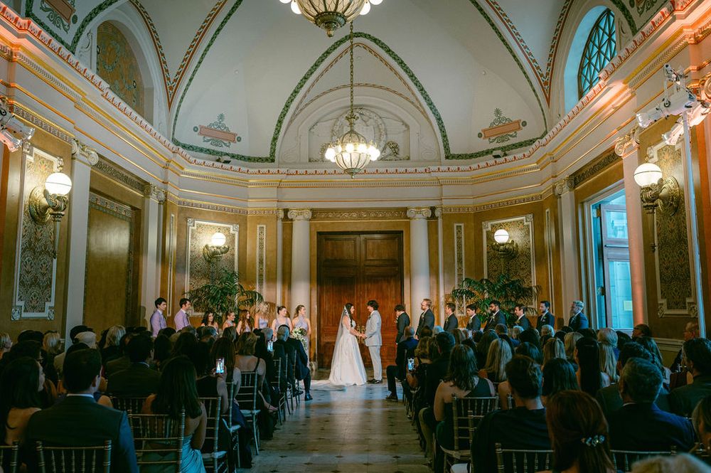 Grand ballroom with crystal chandeliers and arched ceilings set up for a formal wedding ceremony.