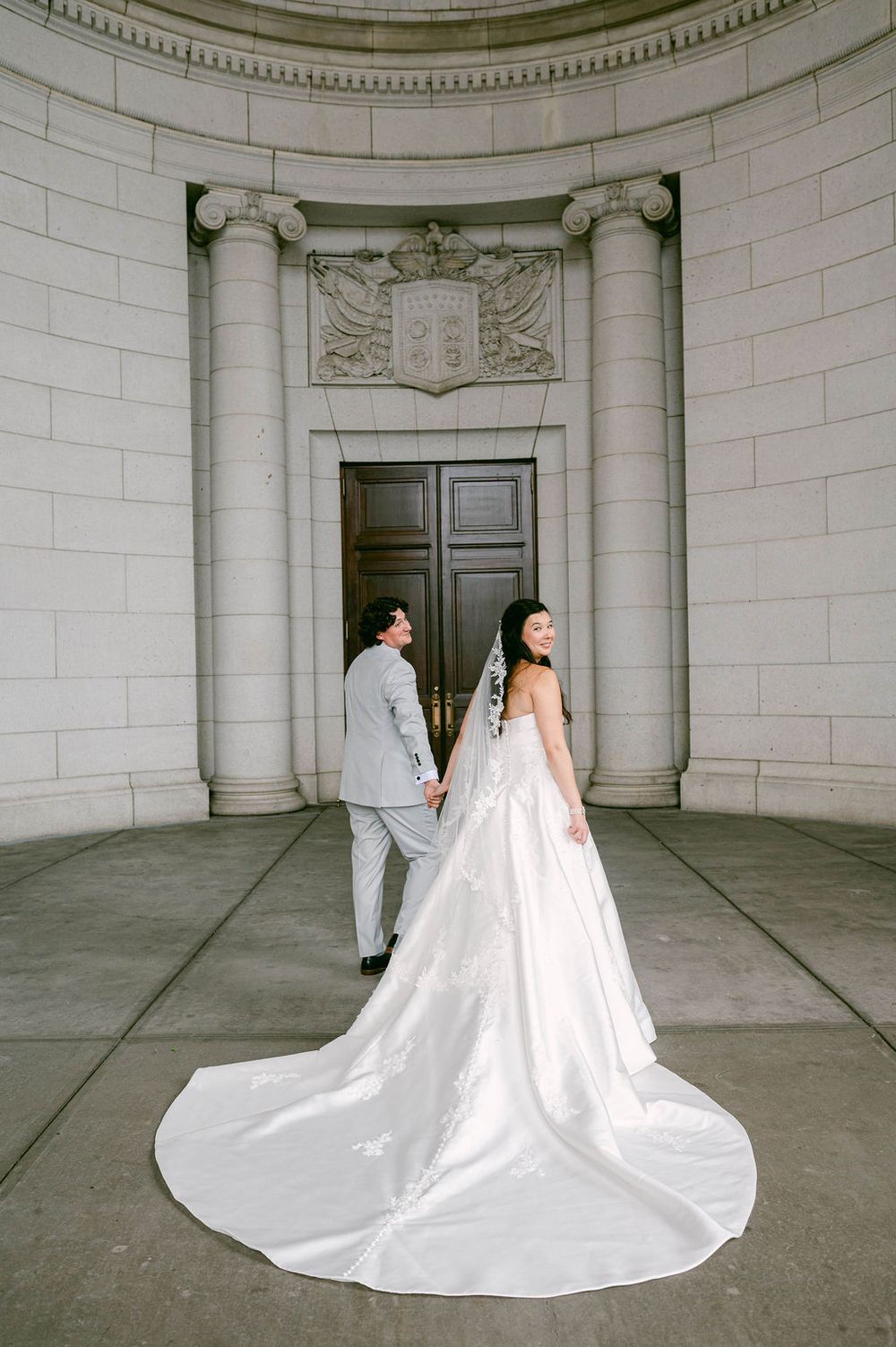 A sequence of elegant bridal portraits showing a flowing white wedding gown with long train in a classical stone rotunda.