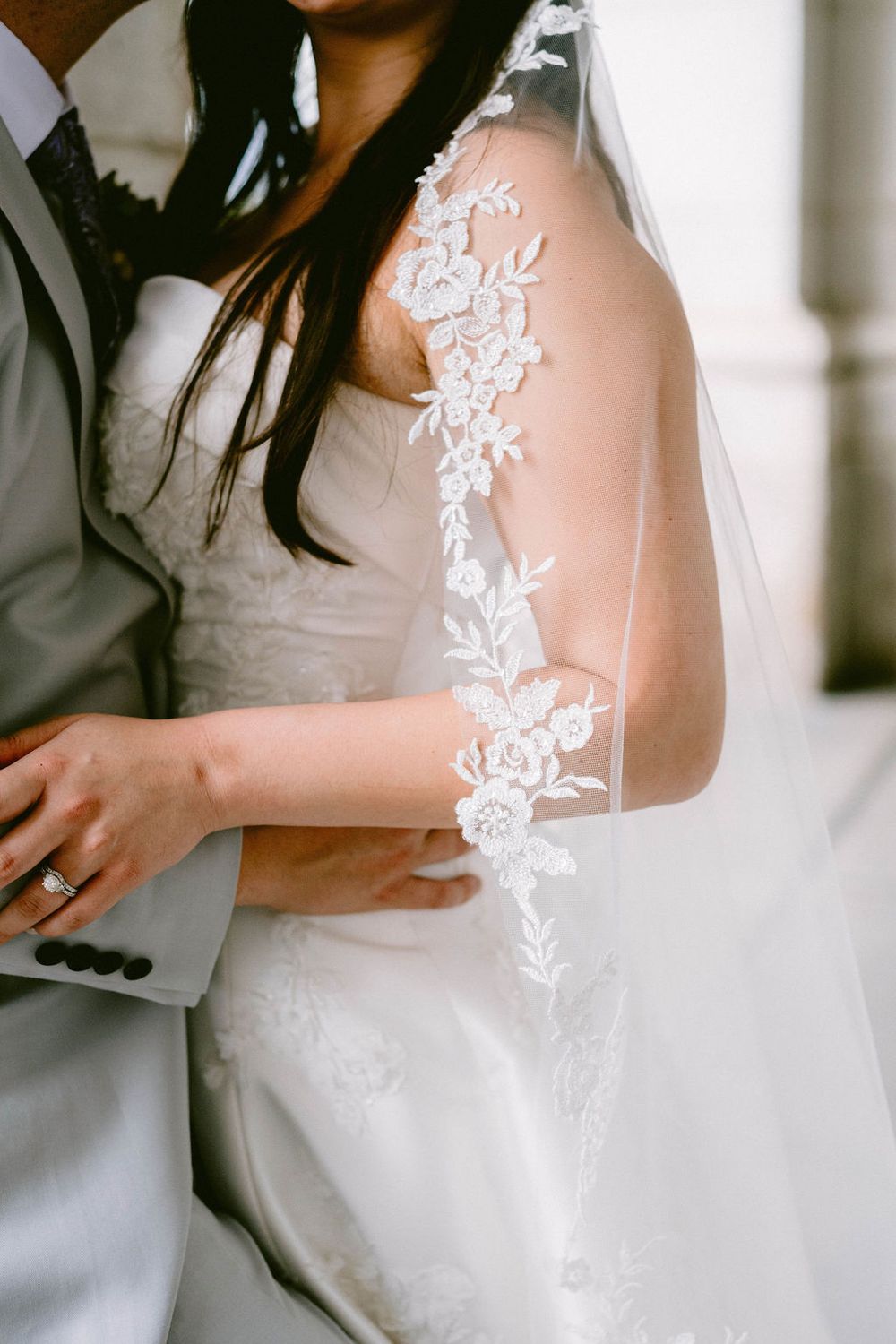 Close-up detail of delicate white lace floral embroidery on a wedding dress.